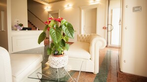 A modern living room with a white sofa, a glass coffee table, and a potted plant. - Hotel Villa Maranello (Maranello)