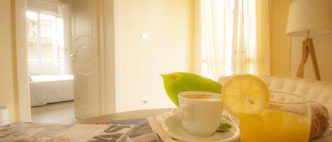 A breakfast setting with a cup of coffee, a glass of orange juice, and a croissant on a table.