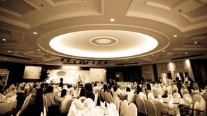 Un espai per a banquets amb taules rodones, un escenari i un disseny de sostre circular.