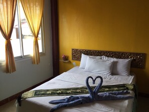 Una habitación de hotel con una cama, paredes amarillas y un cabecero decorativo.