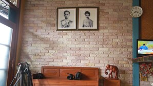 A room with a brick wall, a wooden bench, a tripod, and a television.
