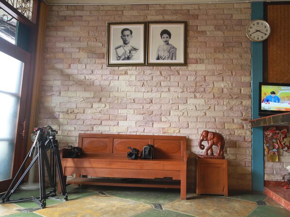 Una habitación con pared de ladrillo, banca de madera, trípode y televisor.