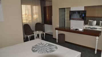 Una habitación de hotel con una cama, un escritorio, una silla, un televisor y una mesita.