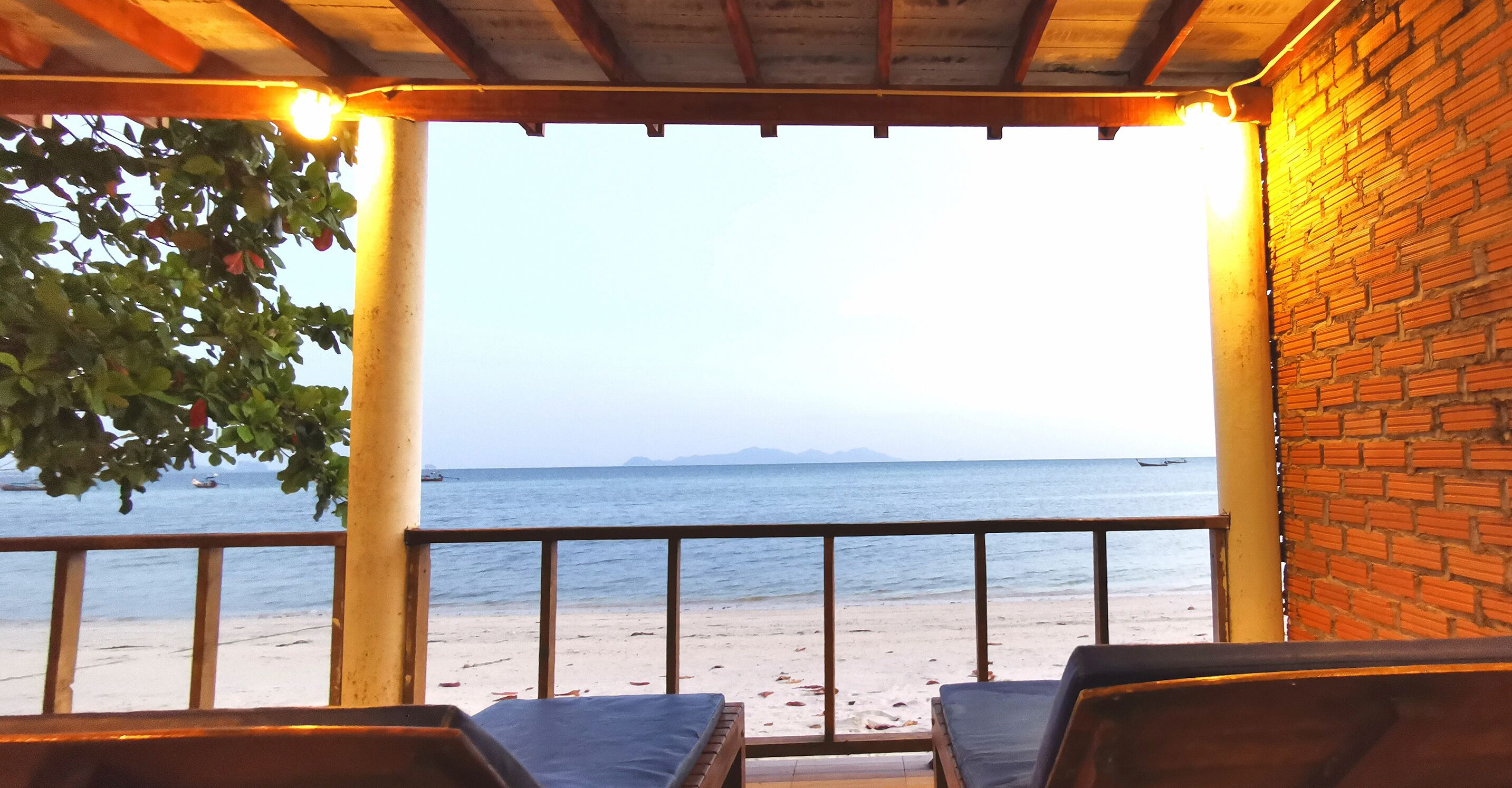 Ein Sitzbereich am Strand mit Blick auf das Meer und ferne Berge.