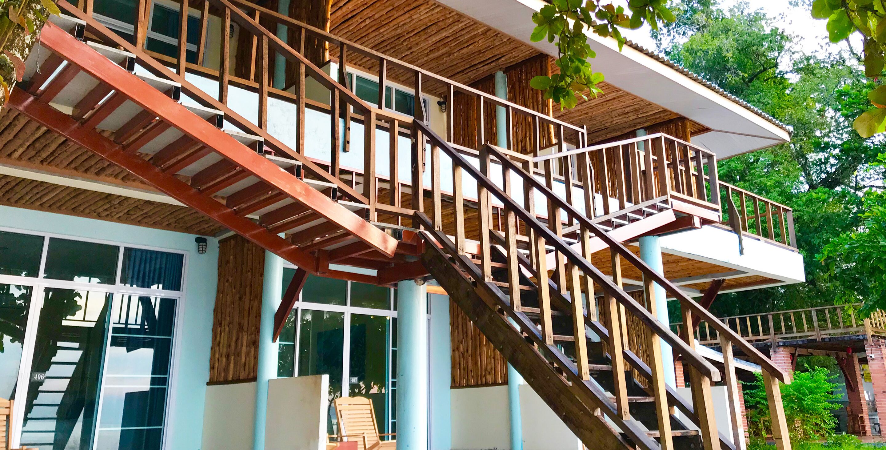 Una escalera de madera de varios niveles con barandilla de metal que da a un balcón.