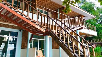 Una escalera de madera de varios niveles con barandilla de metal que da a un balcón.