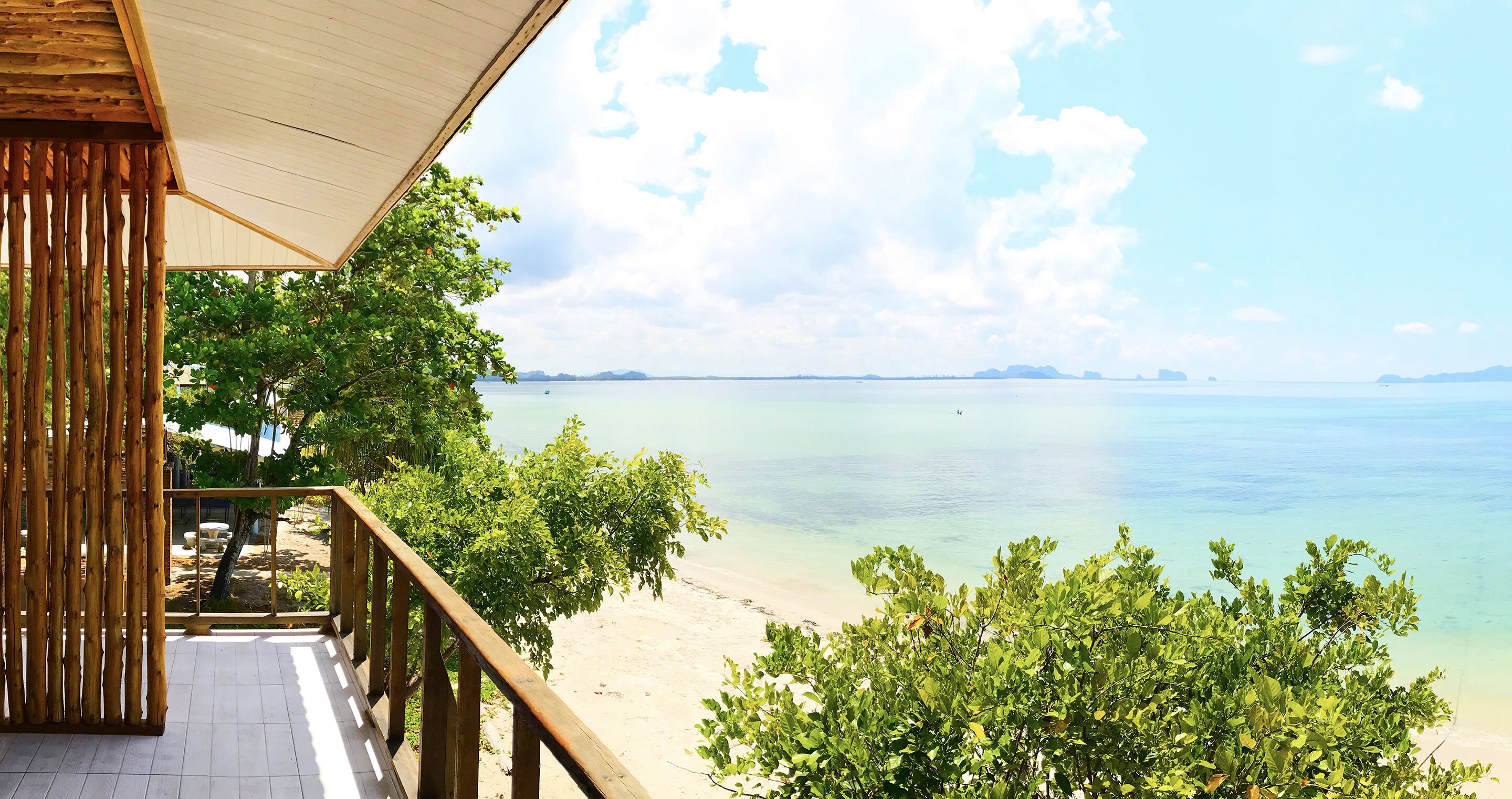 A wooden deck with a view of a beach and ocean.