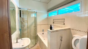 Un baño moderno con ducha de vidrio, lavamanos independiente, bañera y retrete.