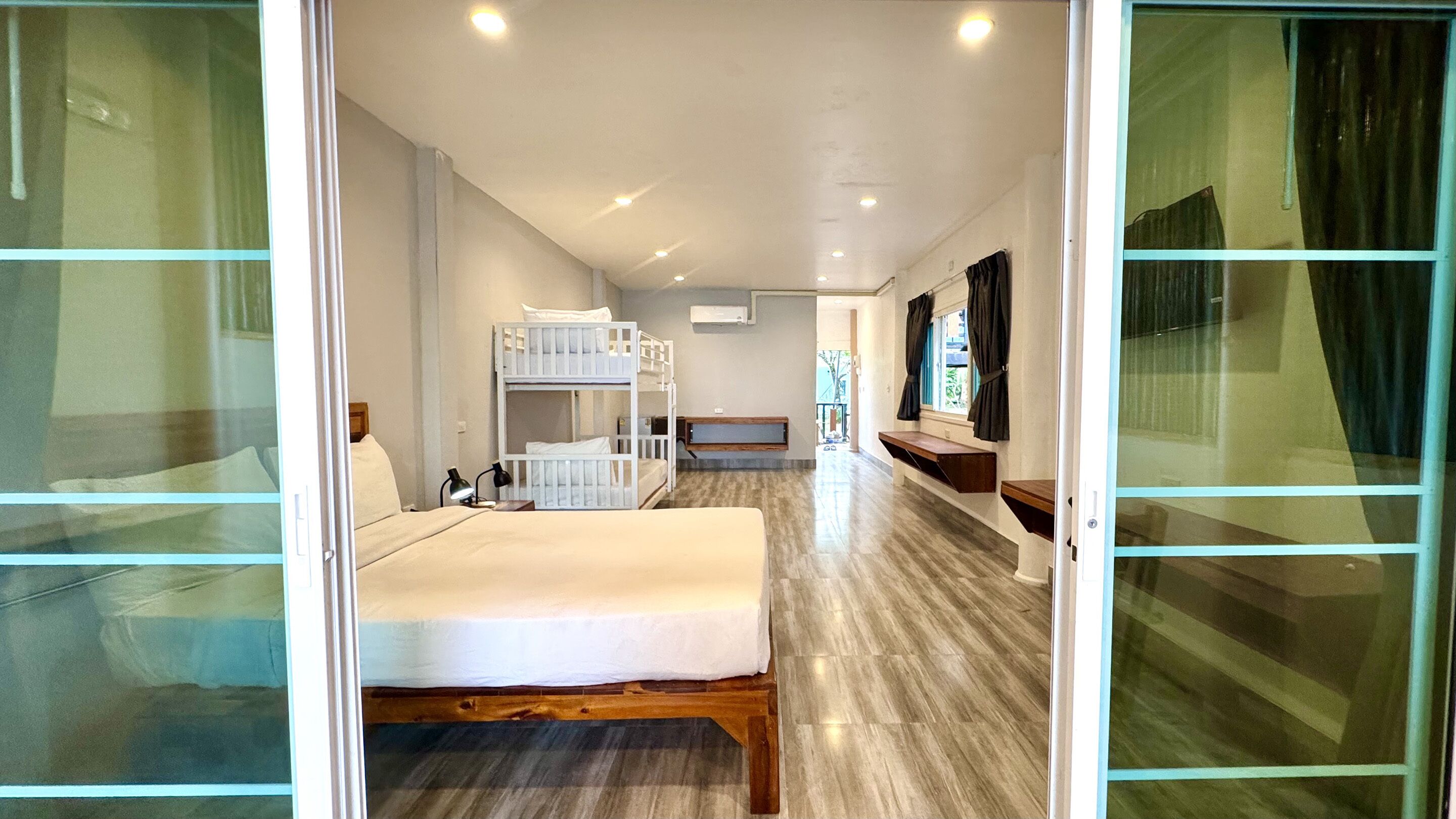 A hotel room with a bunk bed, a desk, and a window with curtains.