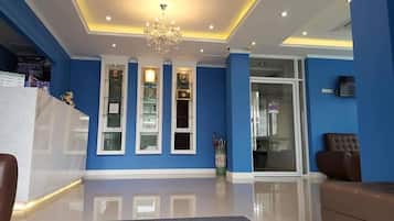 A reception area with a chandelier, blue walls, and a glass door leading to a room.