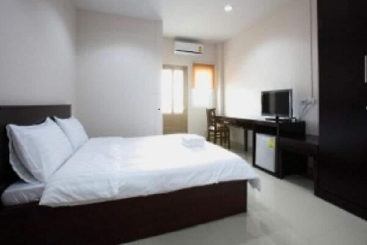 Une chambre d’hôtel avec un lit, un bureau équipé d’un ordinateur et un téléviseur.