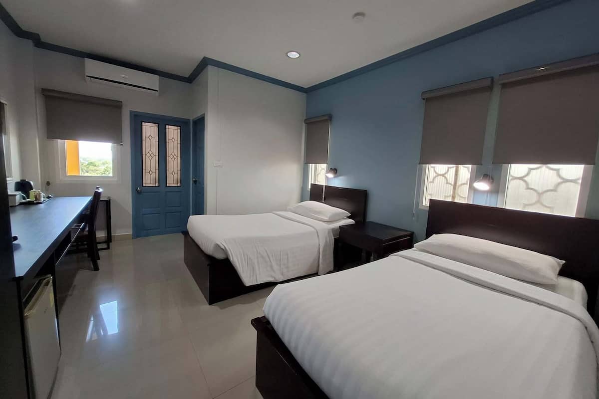Une chambre d’hôtel avec deux lits, un bureau et une chaise.