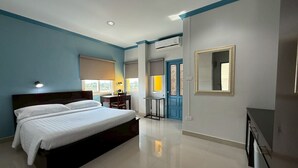 Ein modernes Hotelzimmer mit einem großen Bett, einem Schreibtisch und einem Stuhl. Eine Tür mit blauem Rahmen und ein Spiegel befinden sich an der Wand.