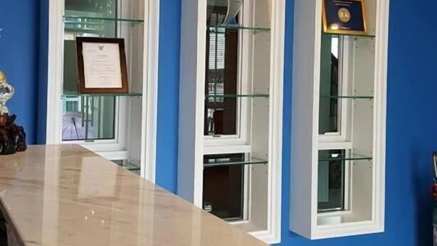 Eine Hotelhalle mit einem Marmor-Rezeptionstresen, blauen Wänden und Glastischen mit gerahmten Gegenständen.
