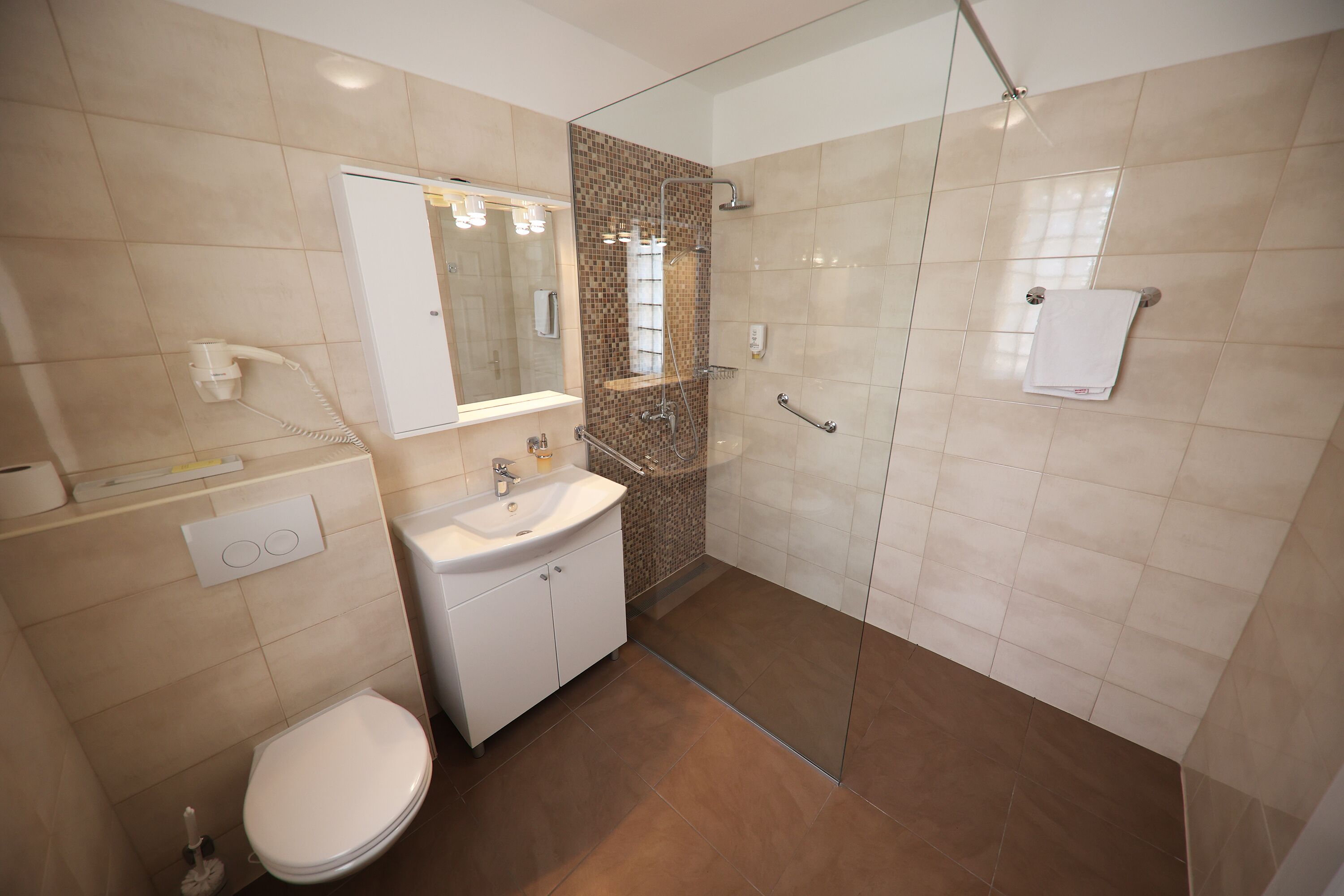 Een moderne badkamer met een douchecabine van glas, een wit wastafelmeubel en een toilet.