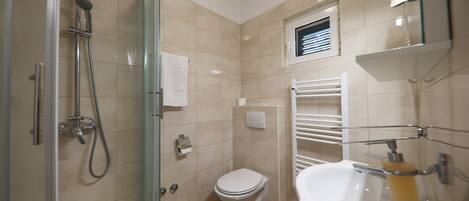 A bathroom with a shower, toilet, and sink.