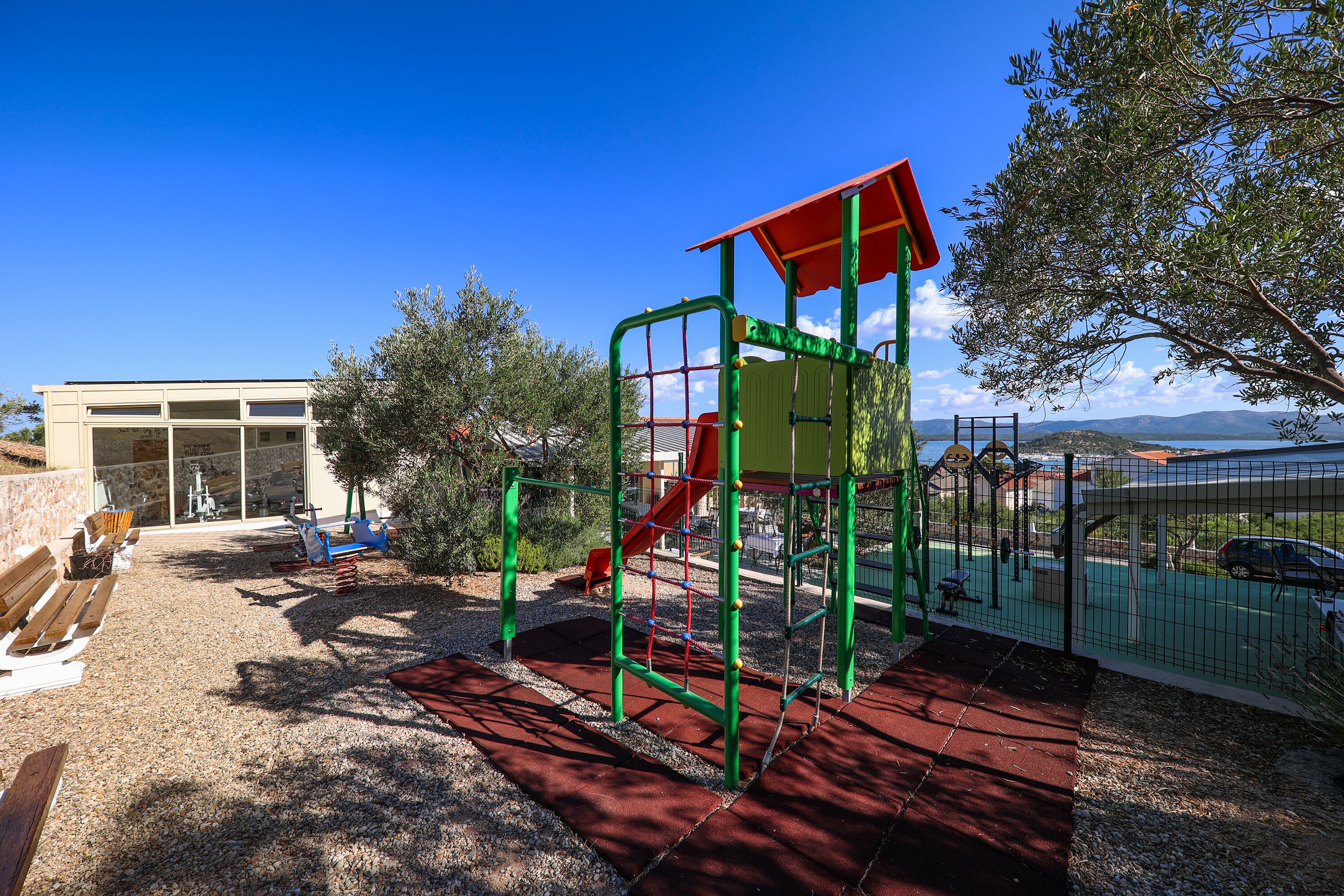 A playground with a climbing structure, a slide, and a covered area.