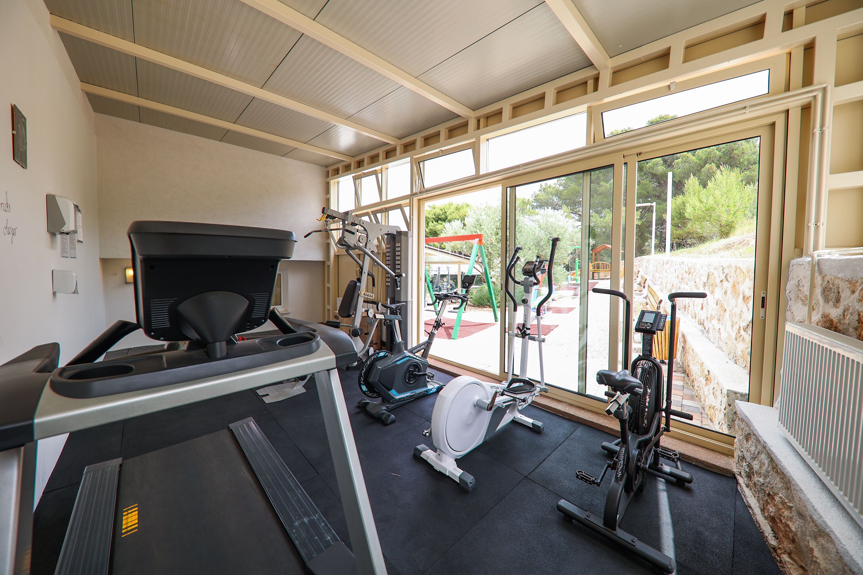 A gym with a treadmill, stationary bikes, and exercise equipment.