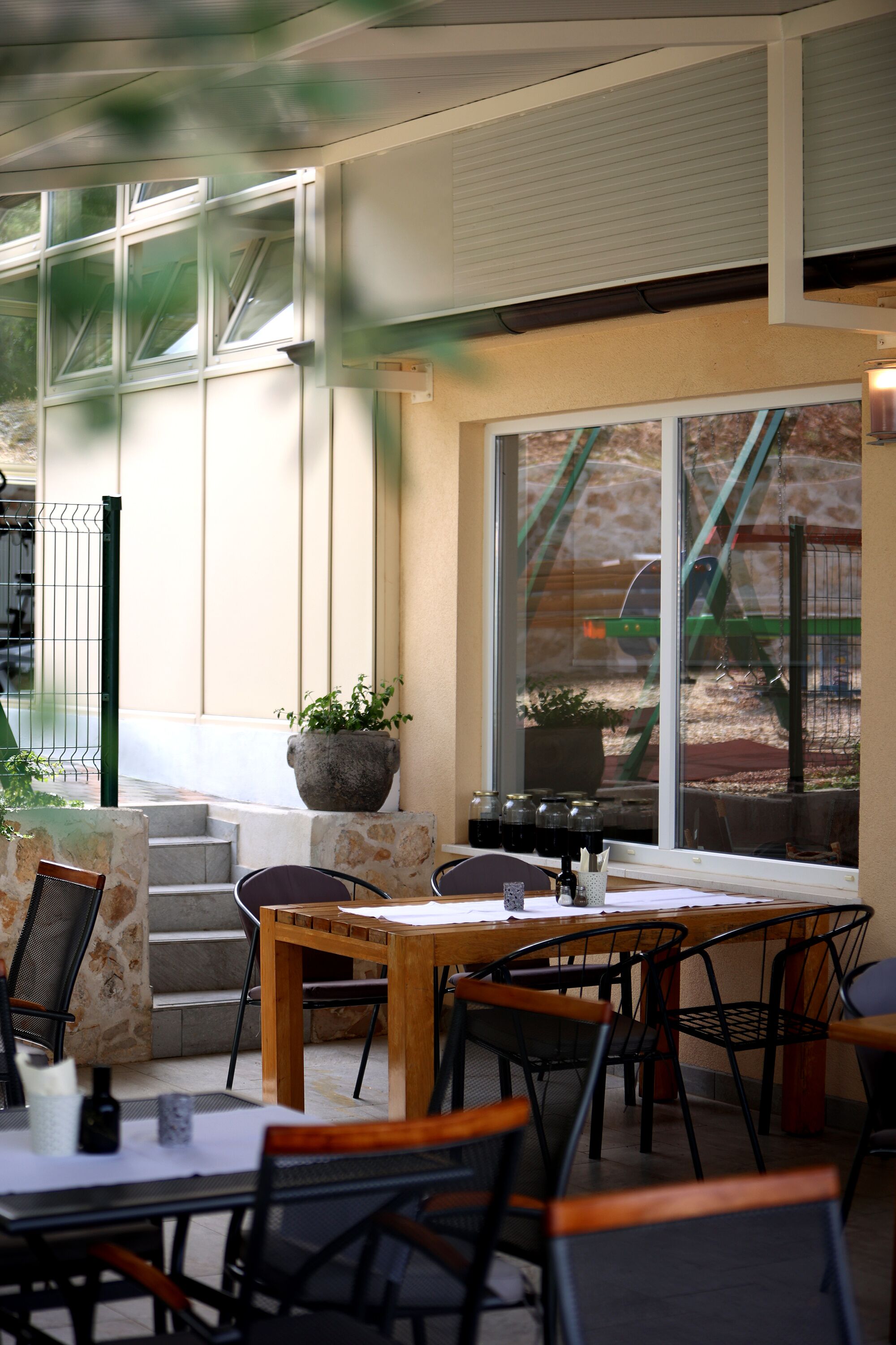 An outdoor seating area with stone steps, wooden tables, and metal chairs.