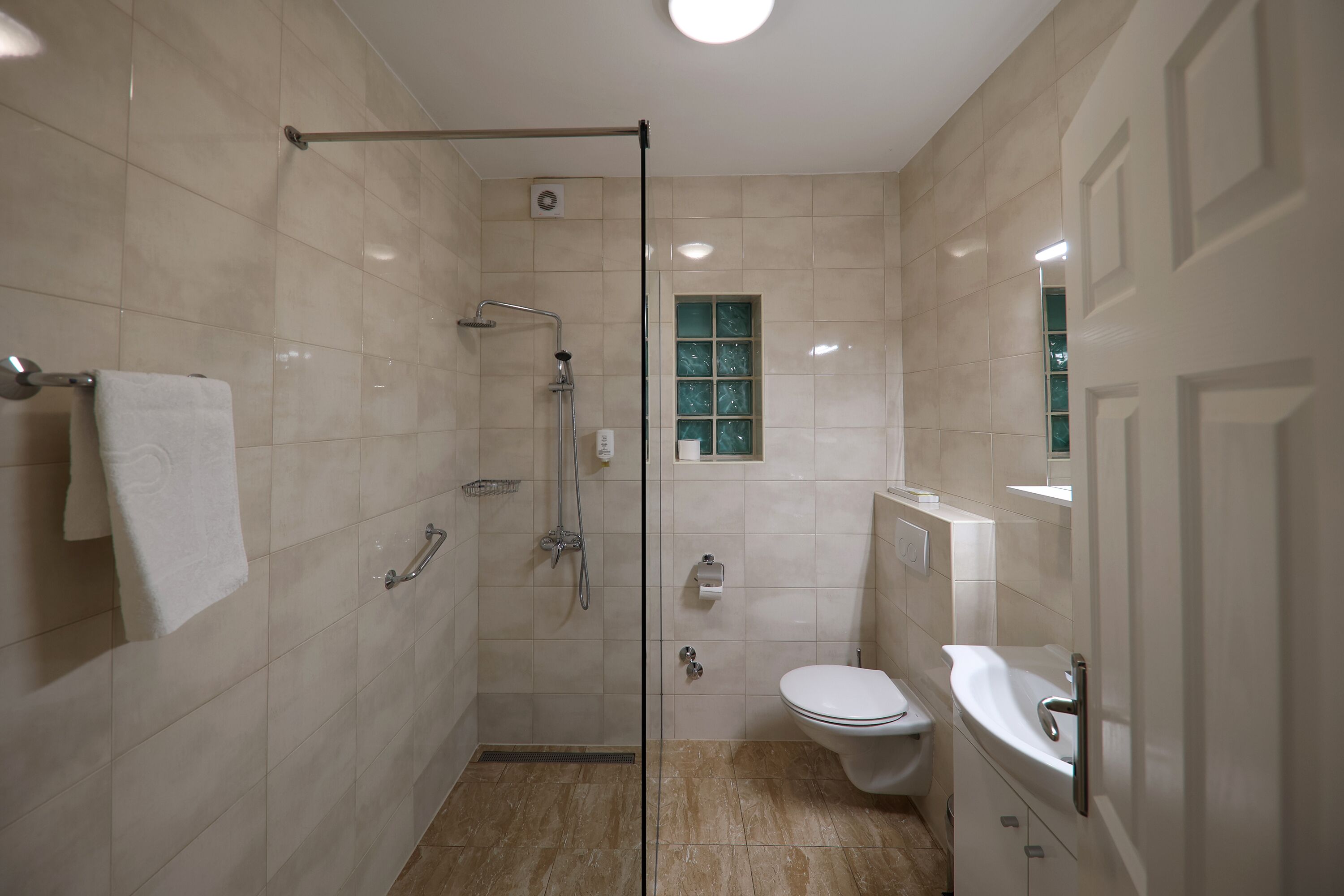 A modern bathroom with a glass-enclosed shower, a toilet, and a sink.