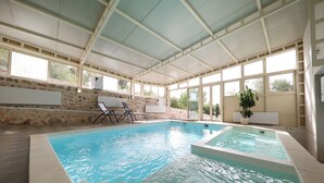 An indoor swimming pool with clear water, stone walls, and large windows. - Hotel Murter (Murter-Kornati)