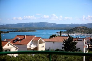 A coastal town with buildings overlooking a bay, boats, and distant mountains. - Hotel Murter (Murter-Kornati)