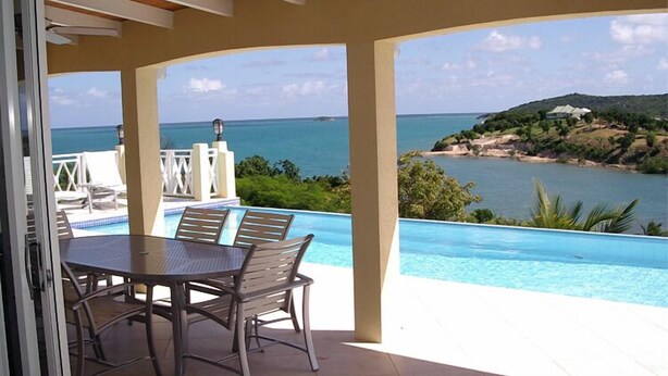 Un espace aménagé au bord de la piscine, offrant une vue sur la mer et une île lointaine.