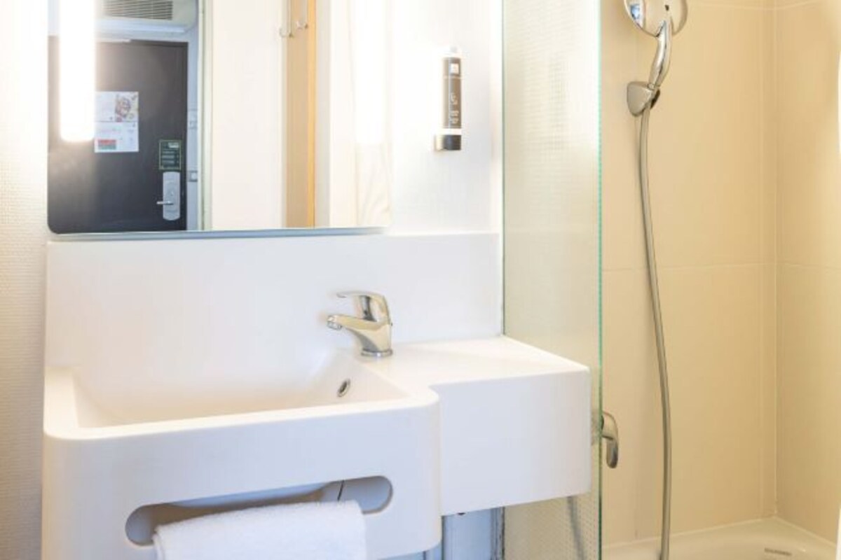 A bathroom with a white sink, mirror, and shower.