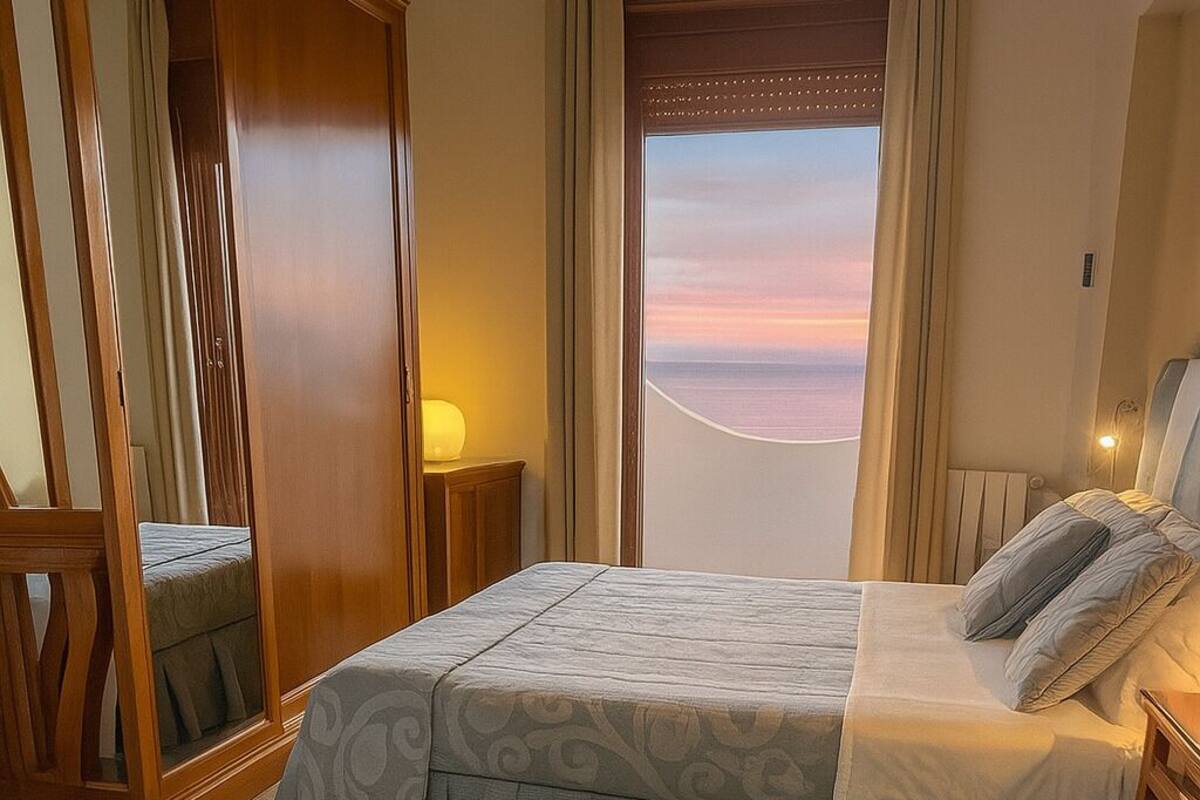 Una habitación de hotel con dos camas, un ventanal con vistas y un armario de madera.