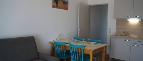 Cocina compacta con una mesa de comedor, sillas y un sofá.