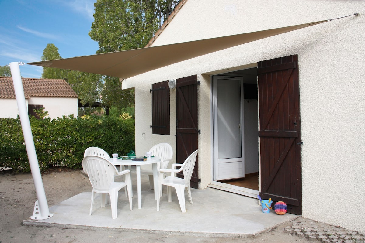 A patio with a table and chairs, a door, and a small pool area.