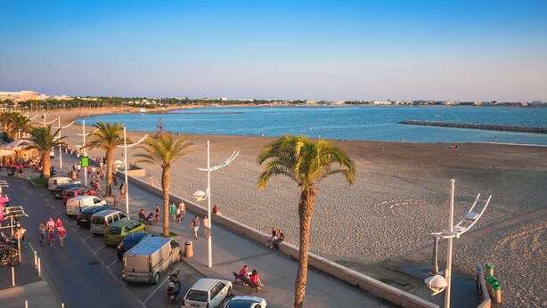 A beachside road with parked cars, palm trees, and a clear view of the sea. - Azureva Le Grau du Roi (Le Grau-Du-Roi)