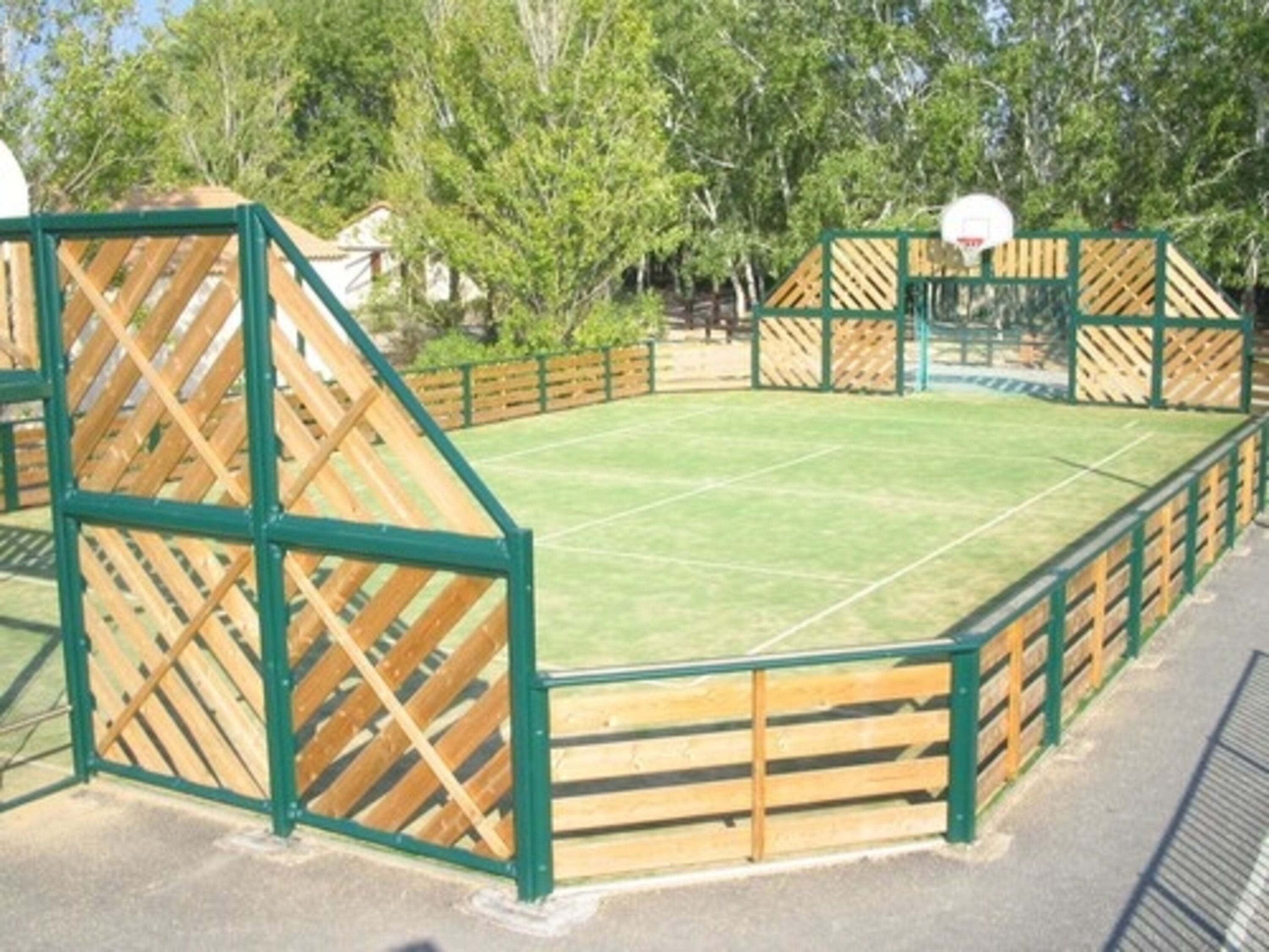 Een omheind sportterrein met een basketbalring.