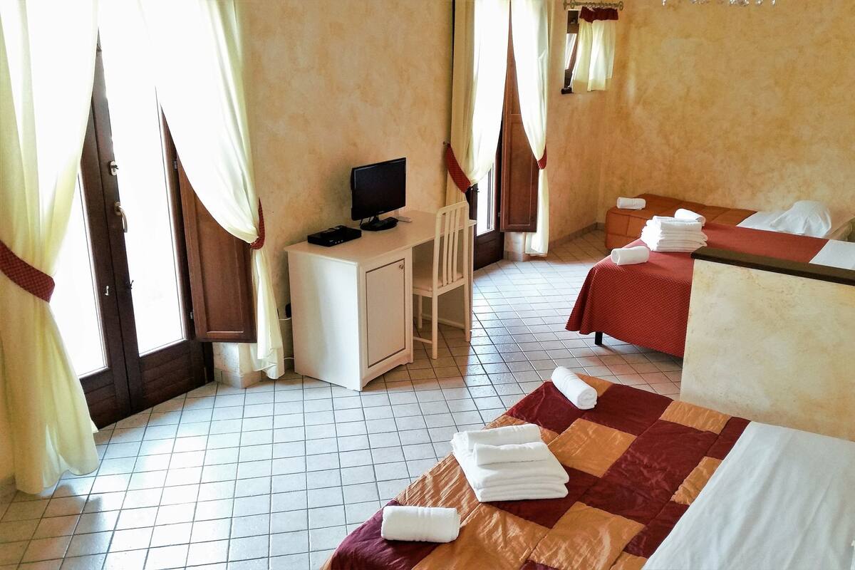 A hotel room with two beds, a TV on a small table, and a tiled floor.