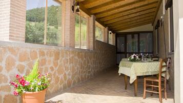 An outdoor patio with a table set for dining, stone walls, and a view of greenery.