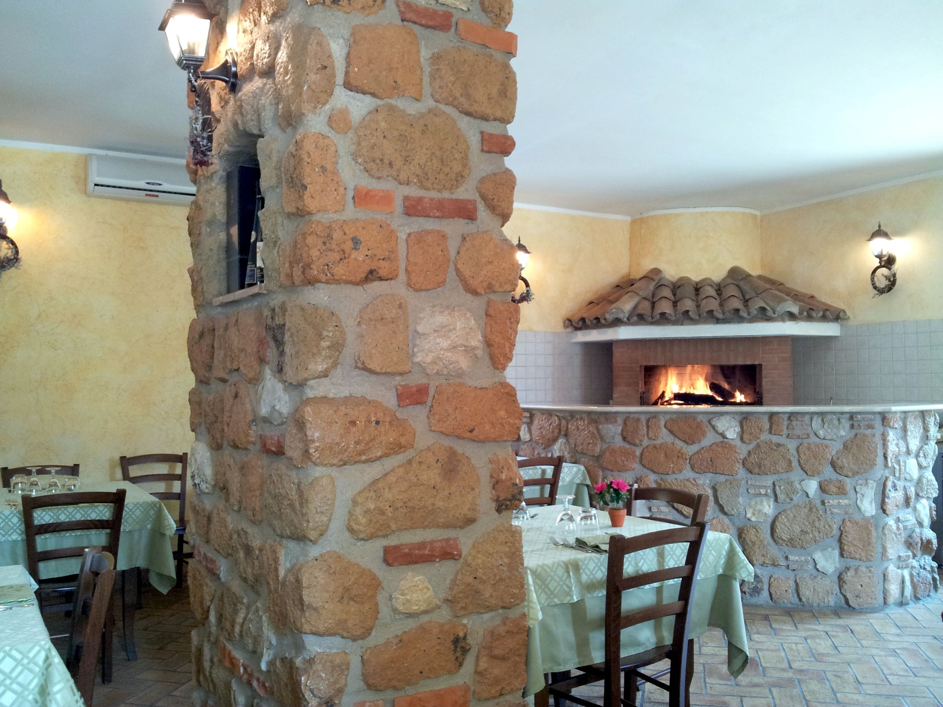 A stone fireplace with a tiled roof, surrounded by stone walls and a tiled floor.