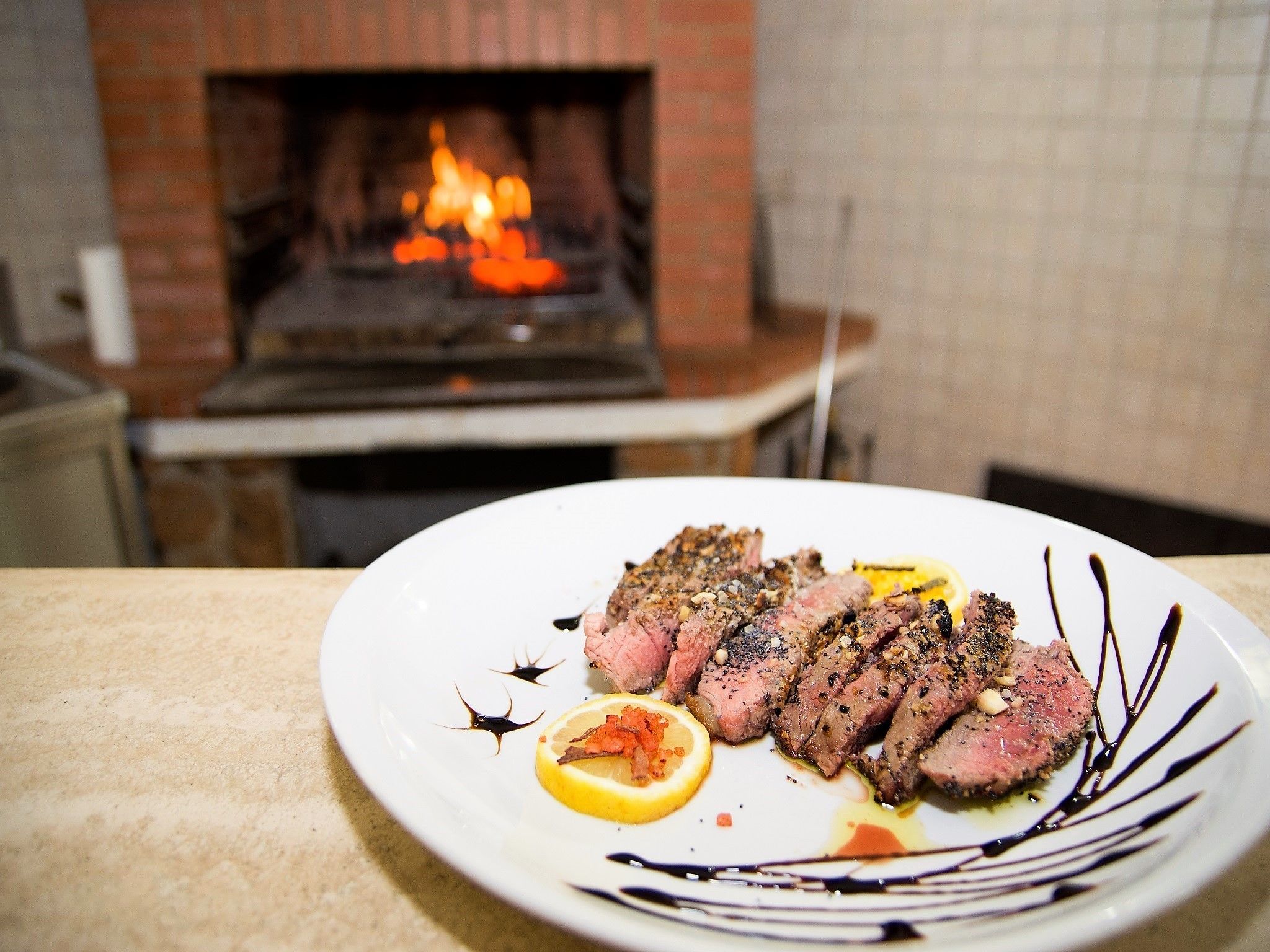 Un plat de carn amb llimona i salsa damunt d'una taula davant una llar de pedra.