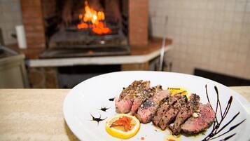 Un plat de carn amb llimona i salsa damunt d'una taula davant una llar de pedra.