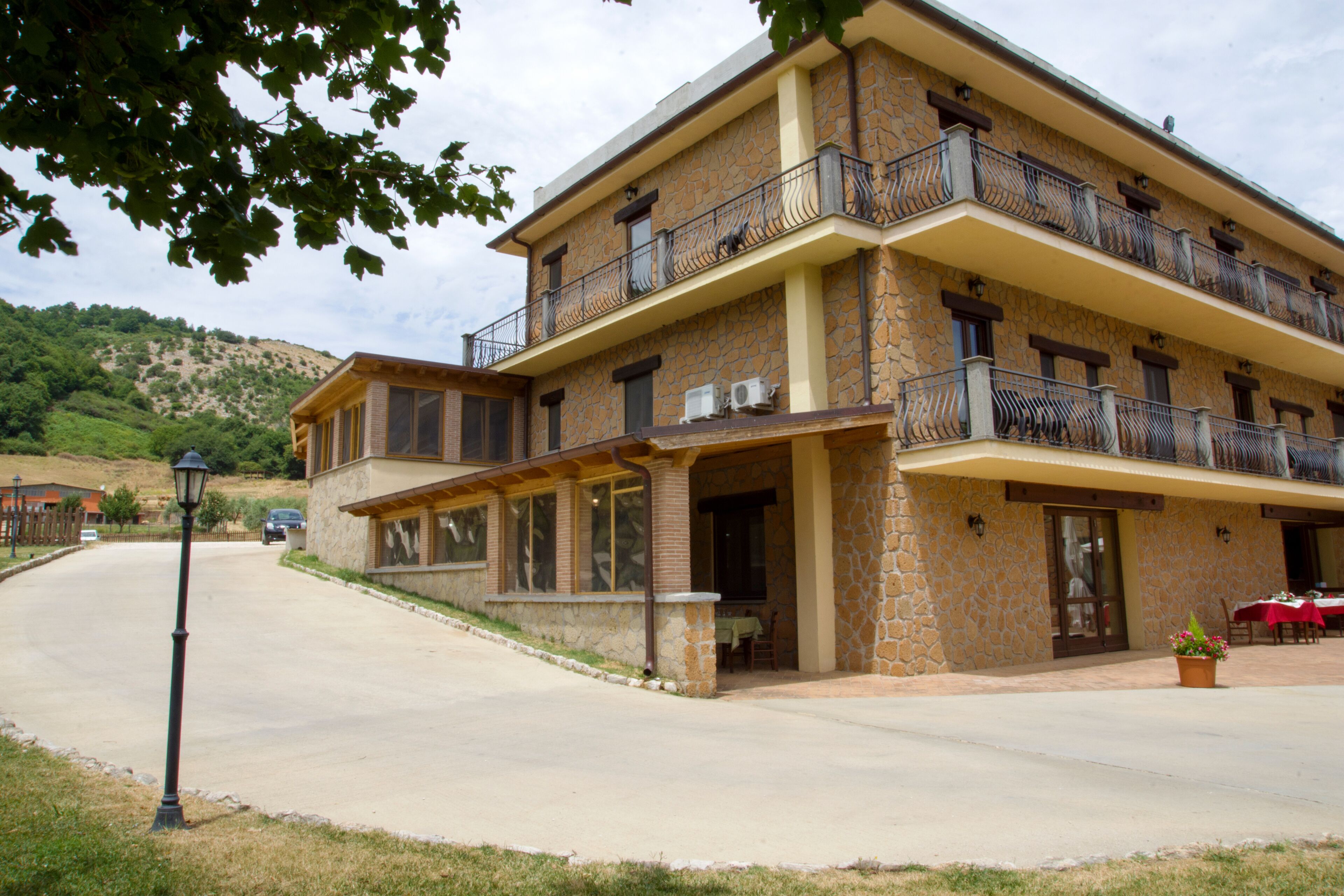A two-story building with a stone facade, balconies with metal railings, and a covered patio area.