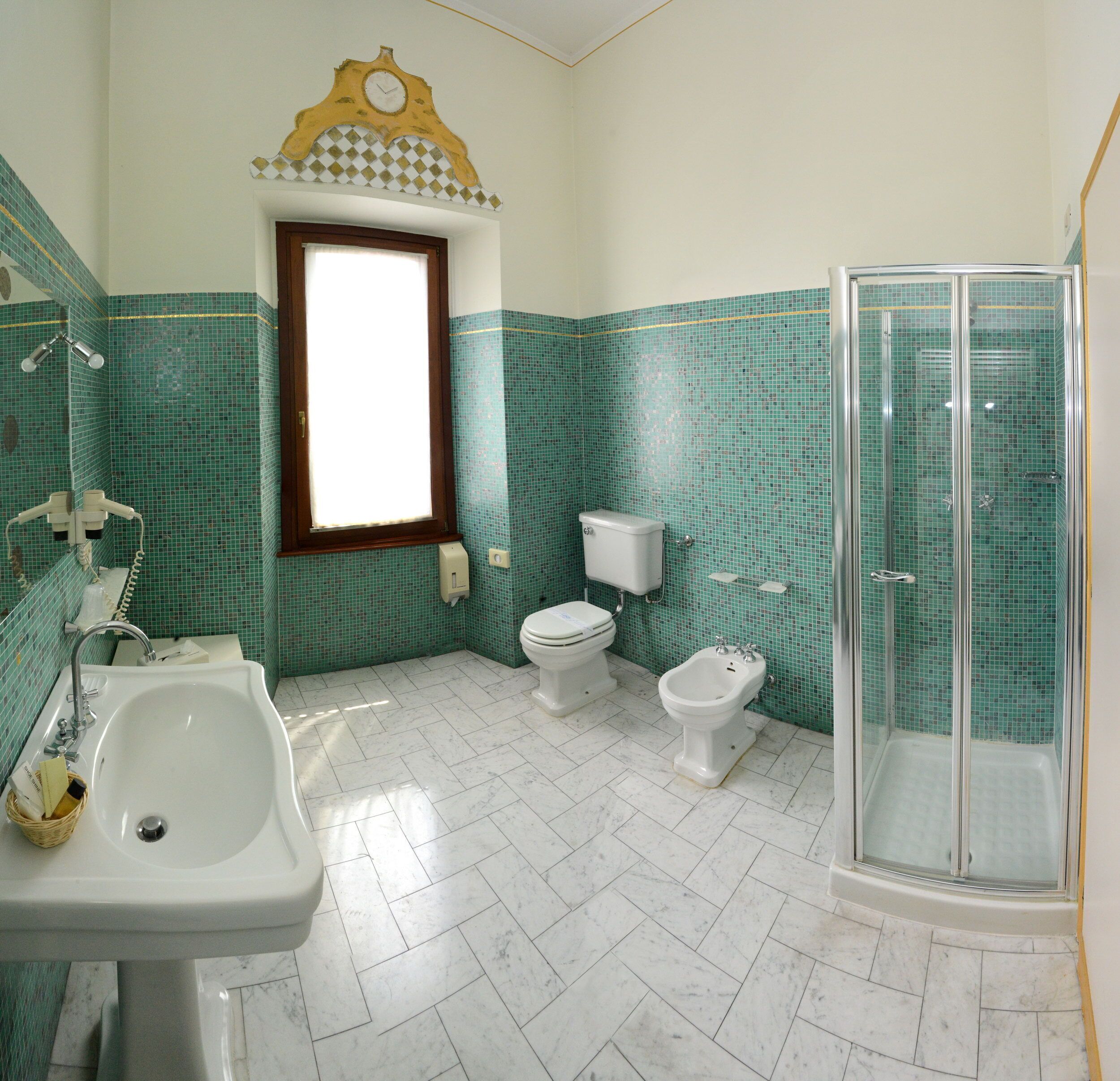 Une salle de bain comprenant un lavabo, deux toilettes, un bidet et une douche à parois de verre.