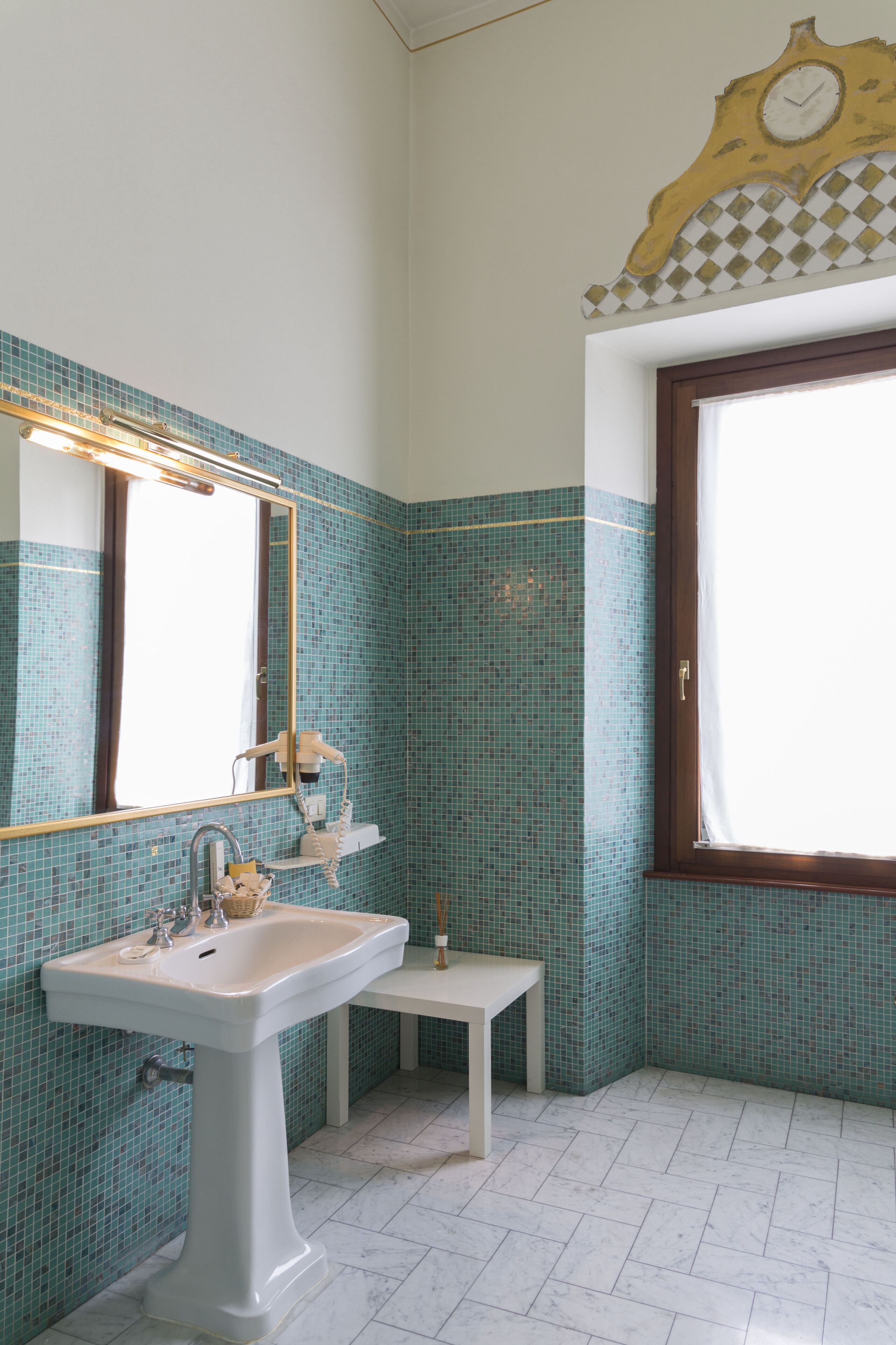 Un baño con lavamanos blanco, espejo y ventana.