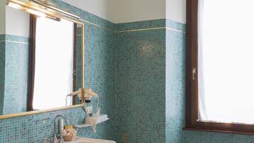 Un baño con lavamanos blanco, espejo y ventana.