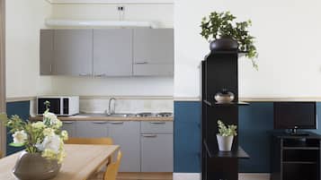 A compact kitchen with grey cabinets, a microwave, a sink, and a dining area with a table and chairs.