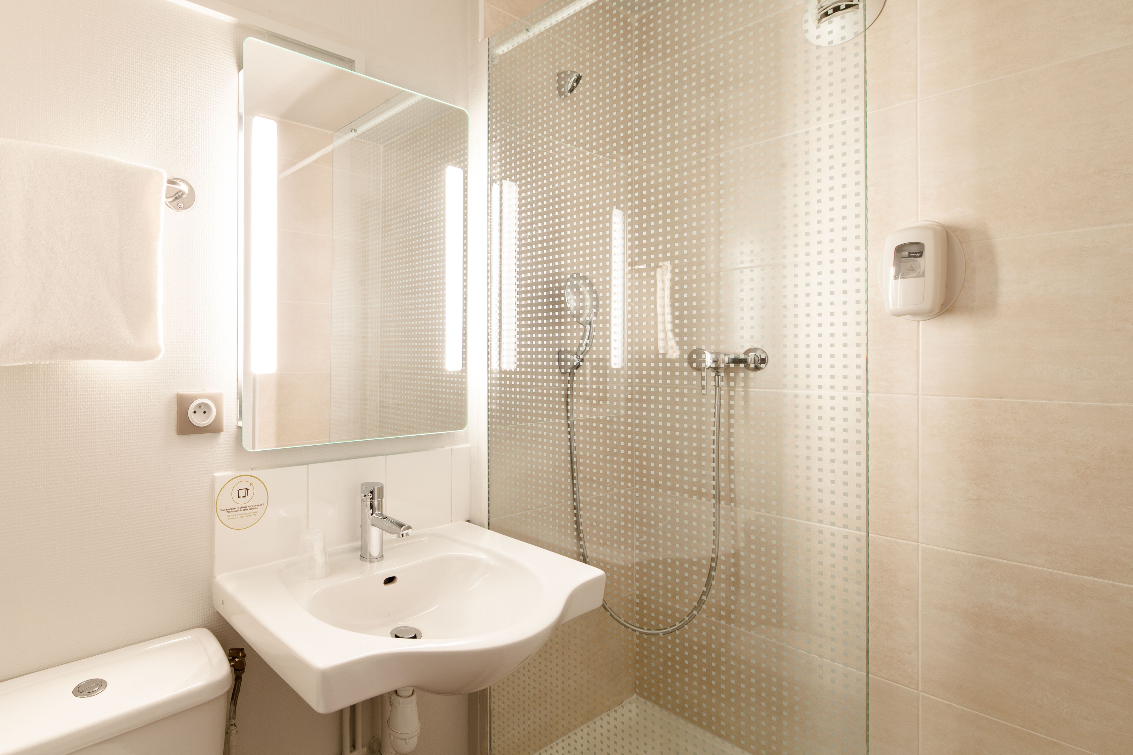 A modern bathroom with a white sink, mirror, and shower.
