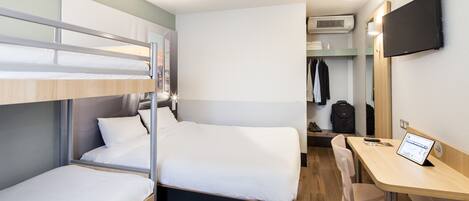 Une chambre d’hôtel compacte équipée de lits superposés, d’un bureau, d’une chaise, d’une télévision et d’une armoire.