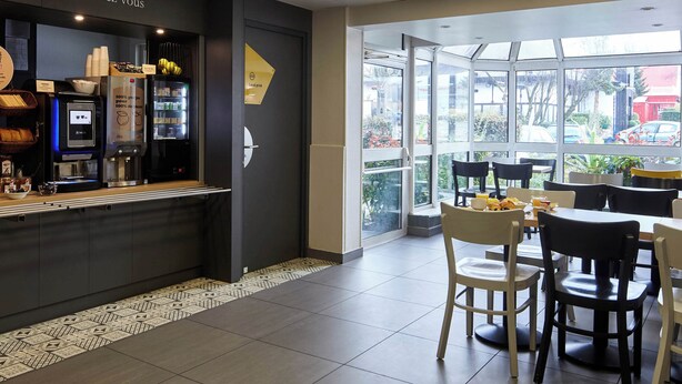 A cafe with a counter, seating area, and large windows. - B&B Hôtel La Queue En Brie (La Queue-en-Brie)