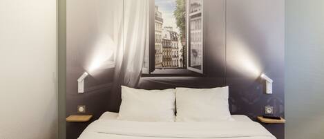 A hotel room with a large bed, two bedside tables, and a view of a cityscape through a window.
