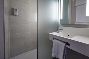 A modern bathroom with a glass shower enclosure, a white sink, and a towel rack. - B&B HOTEL Nantes Parc Expos La Chapelle (La Chapelle-sur-Erdre)