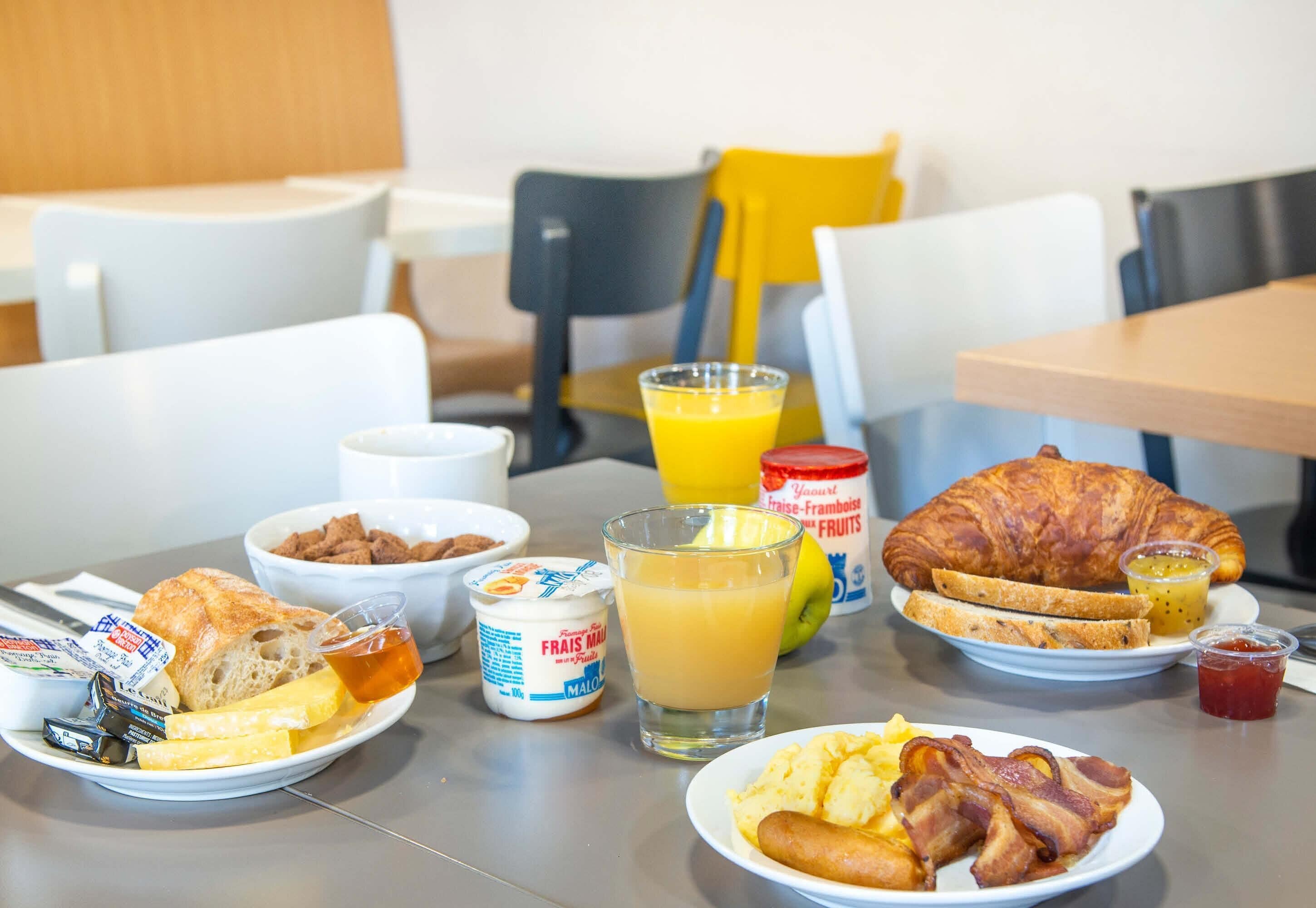 Ein Frühstückstisch mit Croissants, Eiern, Speck und Saft.