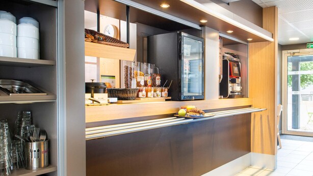 A modern kitchen area with a refrigerator, coffee machine, and various food items on the counter. - B&B HOTEL Nantes Parc Expos La Chapelle (La Chapelle-sur-Erdre)